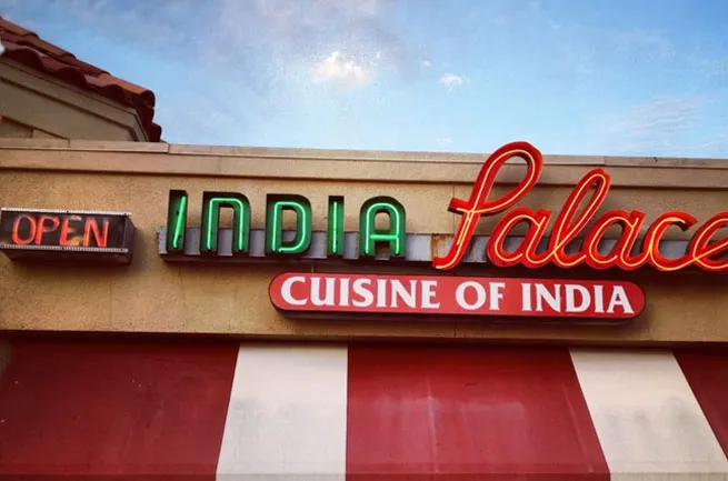 Storefront sign of India Palace, Cuisine of India, in Tulsa with a neon 'Open' sign and red-and-white awning