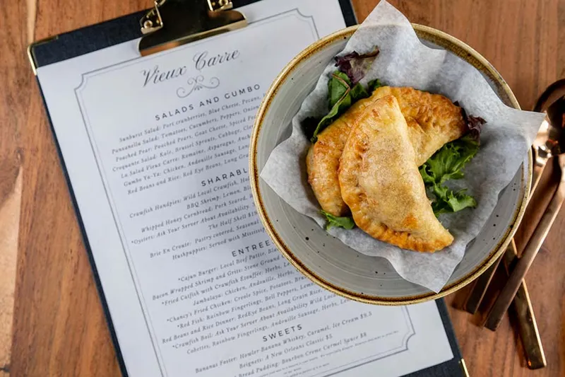 Fried crawfish handpies on a plate next to the Vieux Carré menu