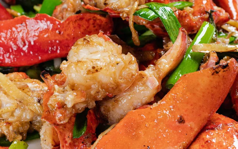 Wok-fried lobster with ginger and scallions plated on a white dish, a signature Cantonese seafood dish at Peach Farm in Boston Chinatown