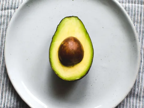 A halved avocado on a plate at ā café