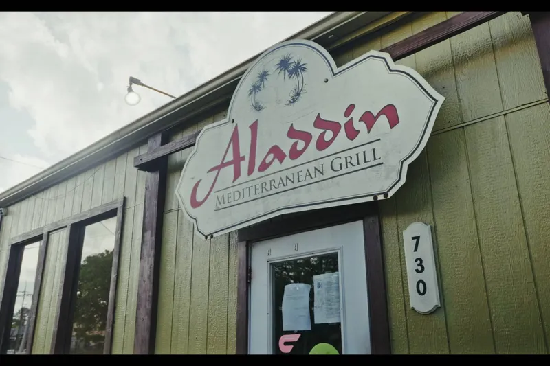Storefront sign for Aladdin Mediterranean Grill beside the building number 730