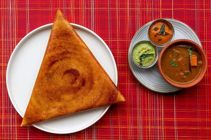 Triangular gunpowder dosa served with sambar and chutneys at Semma