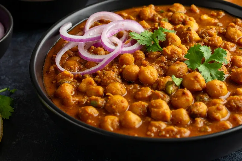 A bowl of chana masala topped with onions and cilantro from Curry Nation.