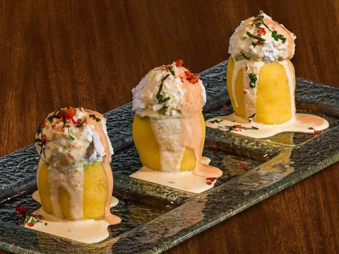 Three causa limena - chilled whipped aji amarillo potato with chicken salad and creams - plated on glass at Los Andes in Providence