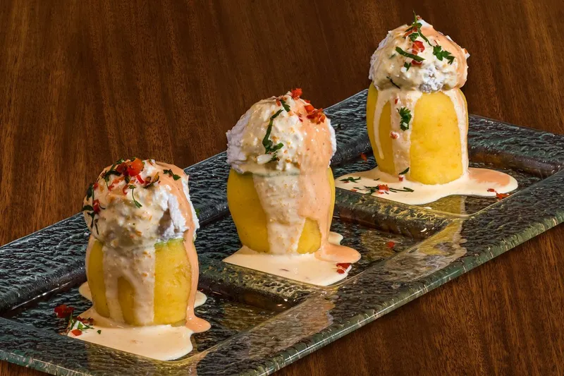 Three causa limena - chilled whipped aji amarillo potato with chicken salad and creams - plated on glass at Los Andes in Providence