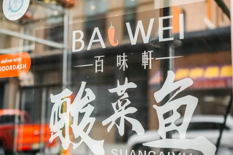 Bai Wei storefront window decal in Philadelphia Chinatown showing the restaurant's name and 百味軒 with a Sichuan suancaiyu (pickled cabbage fish) illustration