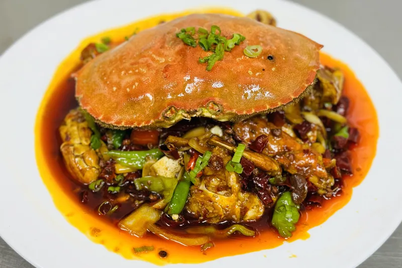 Sichuan spicy crab (香辣蟹) piled in chili oil with dried chilies and scallions on a white plate at X Kitchen (川香阁) in Houston