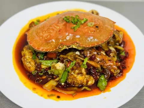 Sichuan spicy crab (香辣蟹) piled in chili oil with dried chilies and scallions on a white plate at X Kitchen (川香阁) in Houston