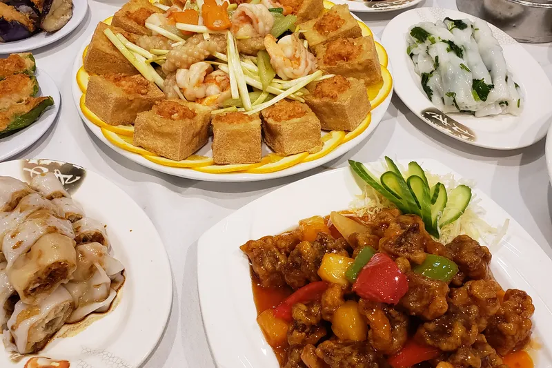 A banquet spread of Cantonese dishes at Ocean City Restaurant in Philadelphia, including stuffed bean curd, rice noodle rolls, sweet-and-sour pork, and dim sum