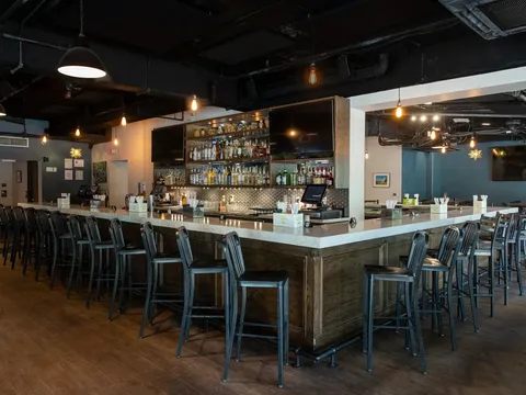 Interior bar and dining room at Cantina 76 on Main Street in Columbia, with a long marble-topped bar, bottle-lined back bar, and hanging Edison-style lights