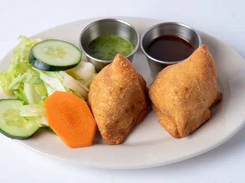 Two vegetable samosas served with salad, green chutney, and tamarind sauce at Namaste Baltimore