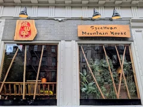 Storefront of Szechuan Mountain House on St Marks Place, East Village, with carved wooden sign and logo and bamboo in the windows