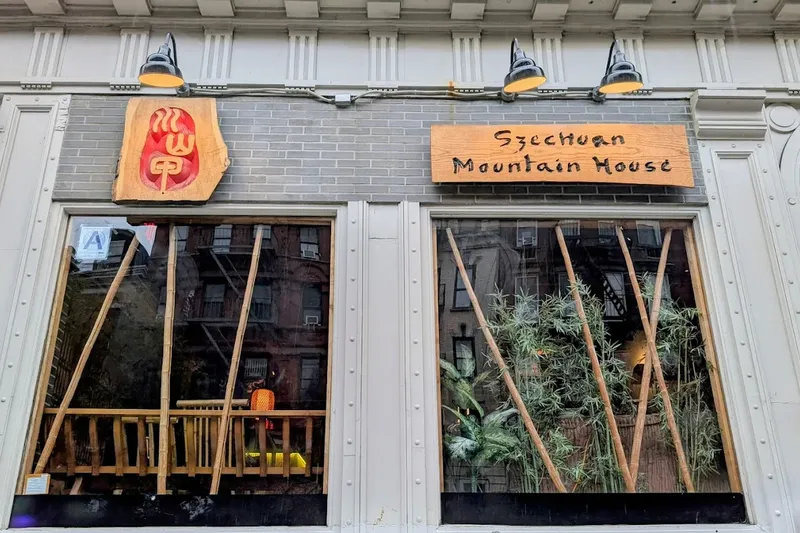 Storefront of Szechuan Mountain House on St Marks Place, East Village, with carved wooden sign and logo and bamboo in the windows