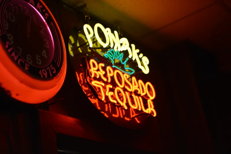 Interior of Ponak's Mexican Kitchen & Bar in Kansas City, showing a glowing neon 'Ponak's Reposado Tequila' sign beside a red 'Since 1975' wall clock