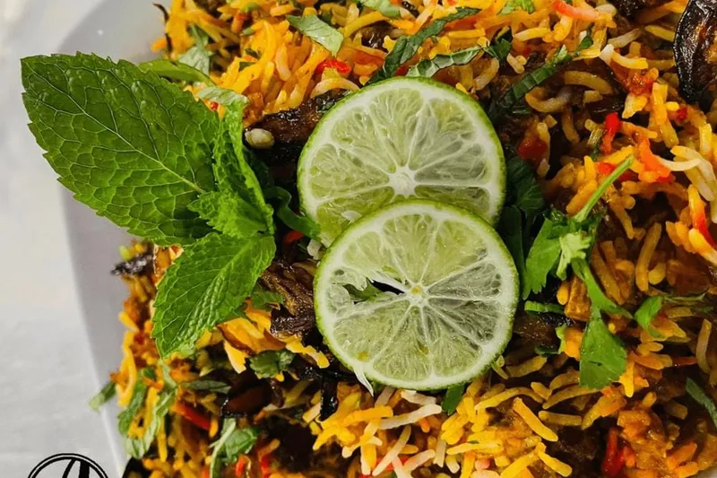 Plate of biryani garnished with mint and lime slices at Aroma Indian Cuisine