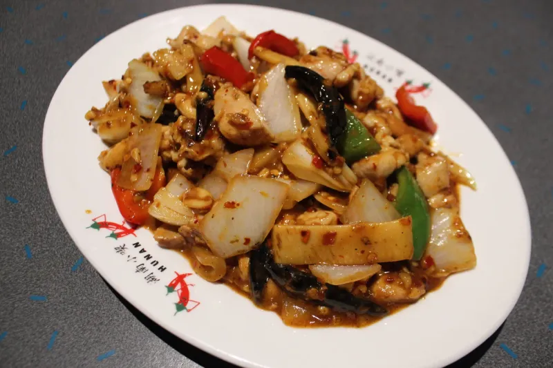 Kung pao chicken with red and green peppers and onions on a Henry's Hunan branded plate