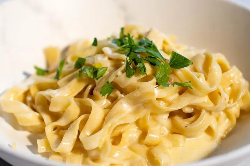 Fettuccine in a creamy sauce garnished with parsley in a white bowl at La Dolce Vita in Cleveland's Little Italy
