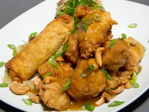 A plate of Leong's Springfield-style cashew chicken — battered fried chicken in brown oyster gravy with cashews and scallions, served with fried rice and an egg roll