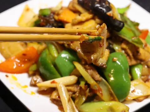 Home-style twice-cooked pork stir-fried with green peppers, red pepper and scallions on a white plate at Najia Cafe