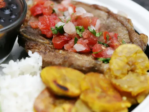 A Cuban plate of palomilla steak topped with tomato and onion, white rice, tostones and black beans at Rincon Criollo in Miami.