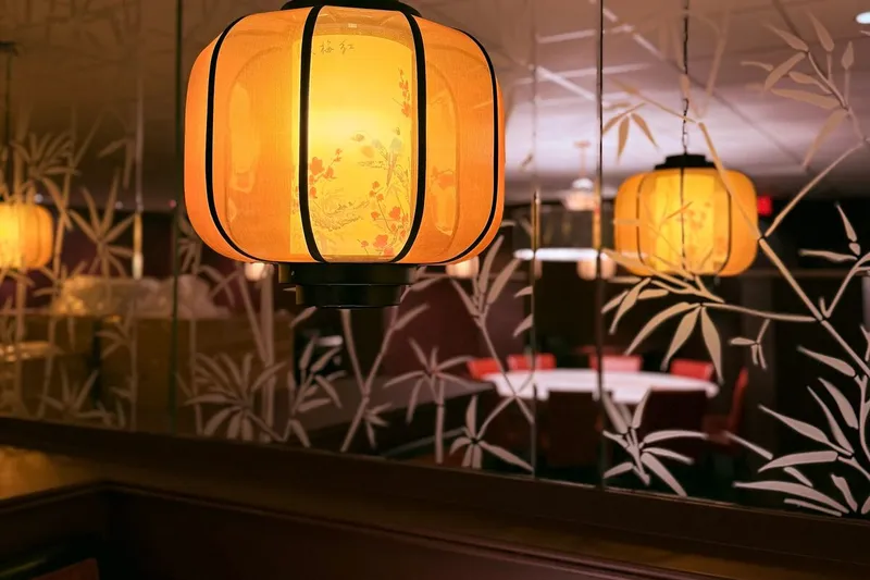 Glowing painted lanterns reflected in mirrored bamboo-patterned walls inside Hunan Lion in Columbus