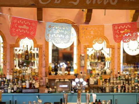 El Pinto's cantina bar with papel picado banners under a beam reading Est. El Pinto 1962