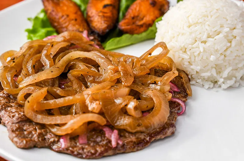 Palomilla steak topped with grilled onions, served with white rice and sweet plantains at Havana Rumba