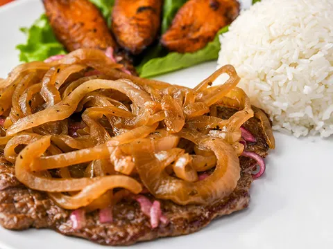 Palomilla steak topped with grilled onions, served with white rice and sweet plantains at Havana Rumba