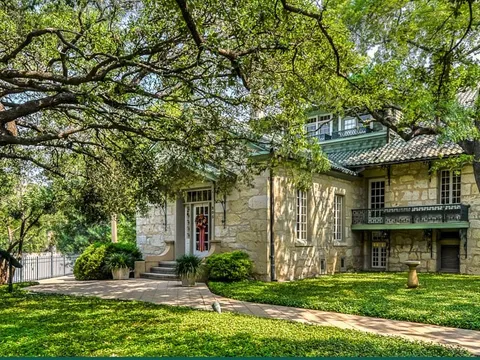 The Guenther House's historic limestone homestead surrounded by oak trees