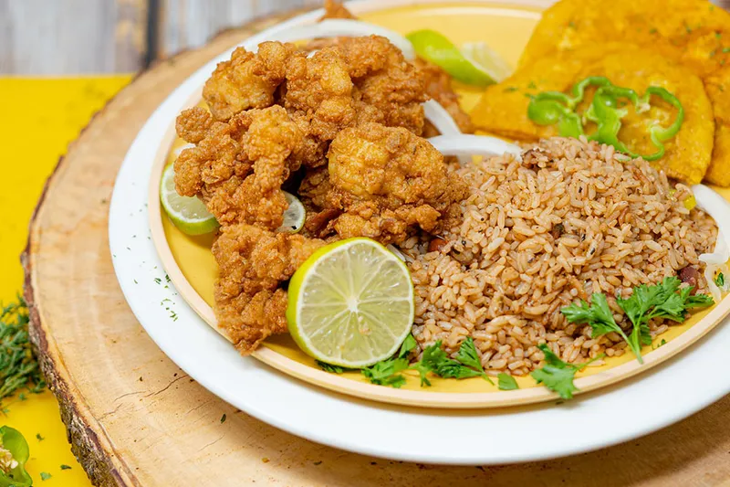 Plate of fried conch with rice and beans, tostones and lime at Chef Creole Seasoned Kitchen in Miami