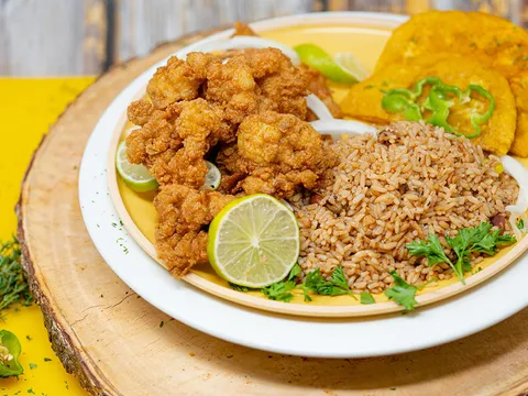 Plate of fried conch with rice and beans, tostones and lime at Chef Creole Seasoned Kitchen in Miami