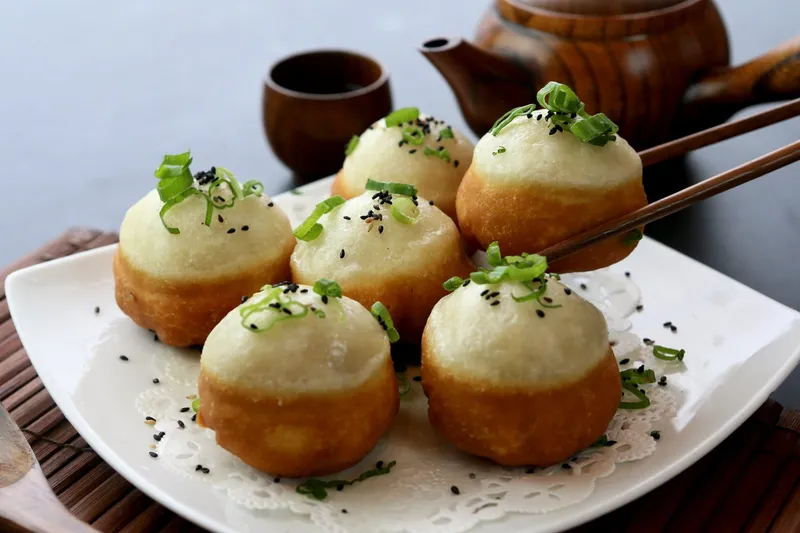 Shanghai-style pan-fried pork buns (sheng jian bao) topped with scallions and sesame seeds at Dumpling Kitchen