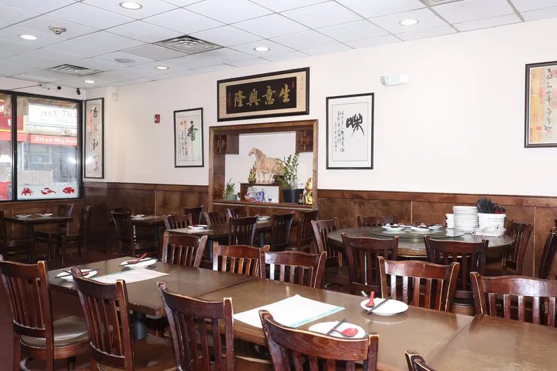 Wood-paneled dining room at Dumpling Cafe in Boston Chinatown with round and square tables, Chinese calligraphy wall art, and a window looking onto Washington Street