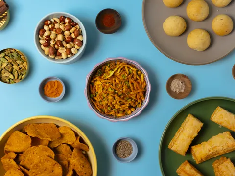 Assortment of Gujarati snacks and farsan at Jay Bharat — sev mixture, dhokla, savory chips, and puff pastry, with bowls of spices