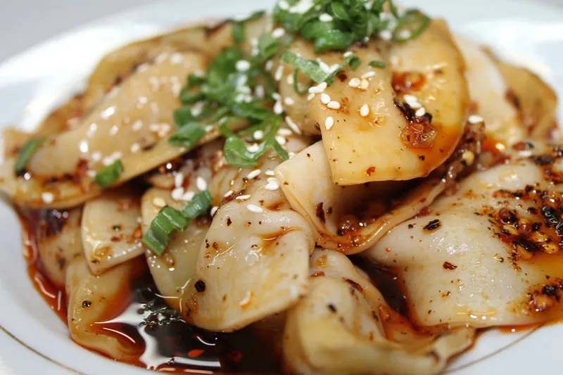 Zhong-style water-boiled dumplings in sweet-and-spicy chili oil topped with sesame seeds and green onions at Gu's Kitchen