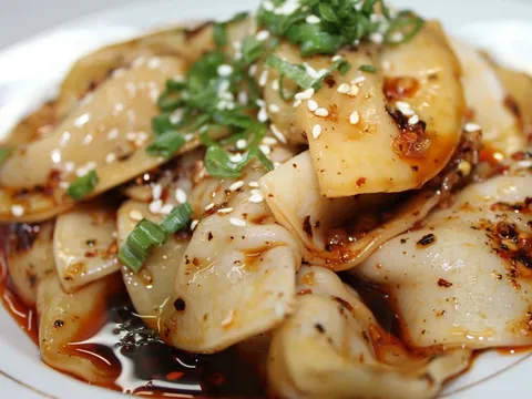 Zhong-style water-boiled dumplings in sweet-and-spicy chili oil topped with sesame seeds and green onions at Gu's Kitchen