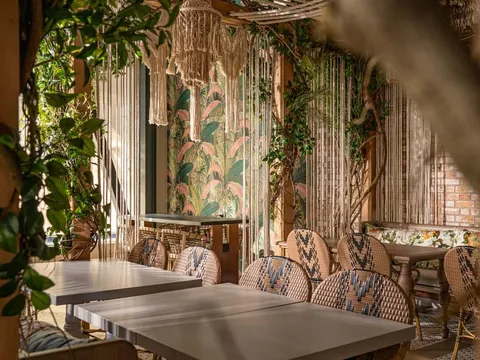 Copra dining room with tropical plants, patterned walls, and set tables