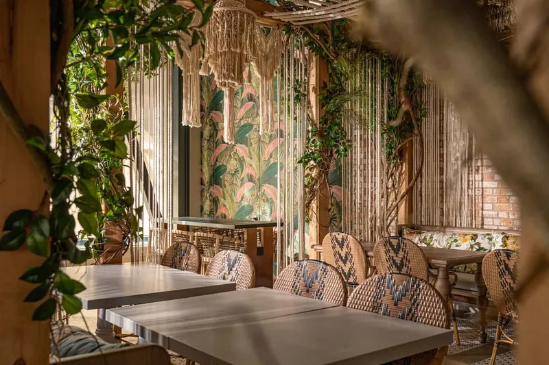 Copra dining room with tropical plants, patterned walls, and set tables