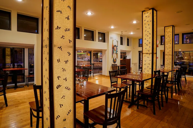 Dining room at Ethiopic Restaurant with fabric columns printed in Amharic script and wood floors, Washington DC