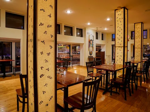 Dining room at Ethiopic Restaurant with fabric columns printed in Amharic script and wood floors, Washington DC