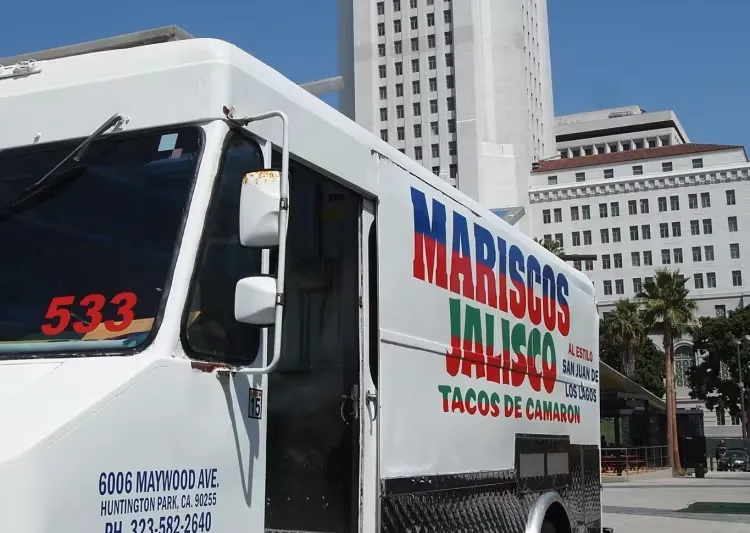 The Mariscos Jalisco taco truck — white with red-and-green "Mariscos Jalisco / Tacos de Camaron" lettering — parked in front of Los Angeles City Hall