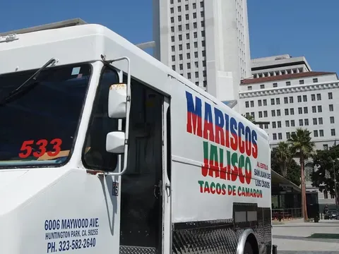 The Mariscos Jalisco taco truck — white with red-and-green "Mariscos Jalisco / Tacos de Camaron" lettering — parked in front of Los Angeles City Hall