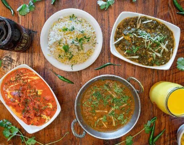 Overhead spread of rice, curries, naan, and mango lassi at Masti Indian Street Eats