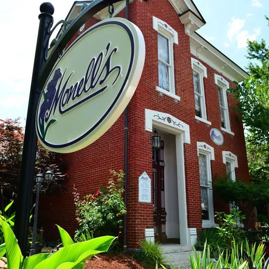 Exterior of Monell's, a red-brick 1905 Victorian house in Germantown, with the oval Monell's sign hanging out front