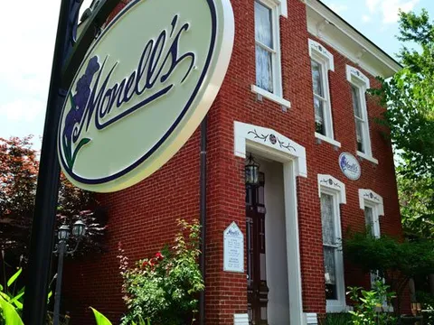 Exterior of Monell's, a red-brick 1905 Victorian house in Germantown, with the oval Monell's sign hanging out front