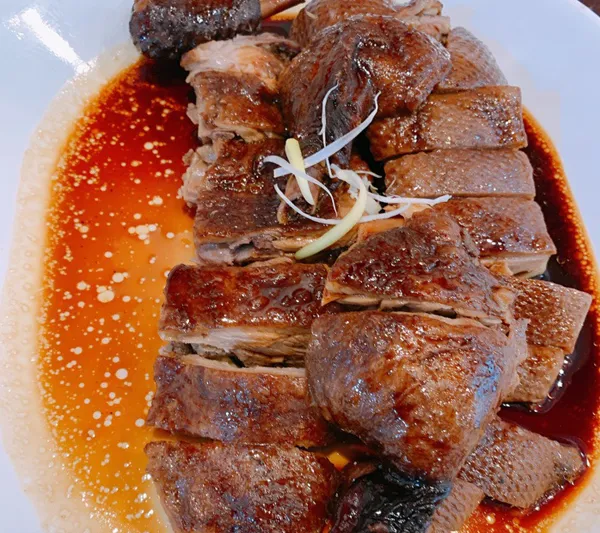 Plate of sliced roast duck in savory sauce garnished with ginger and scallion at Go 4 Food
