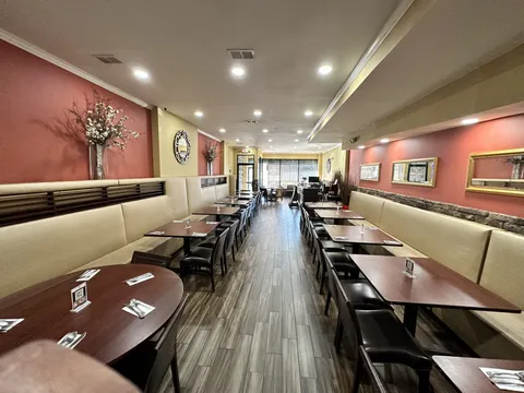Interior dining room of Golconda Chimney in Jersey City, with beige banquette seating, dark wood tables set with cutlery, terracotta walls and framed mirrors