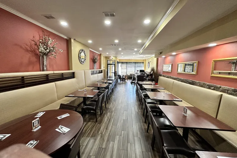 Interior dining room of Golconda Chimney in Jersey City, with beige banquette seating, dark wood tables set with cutlery, terracotta walls and framed mirrors