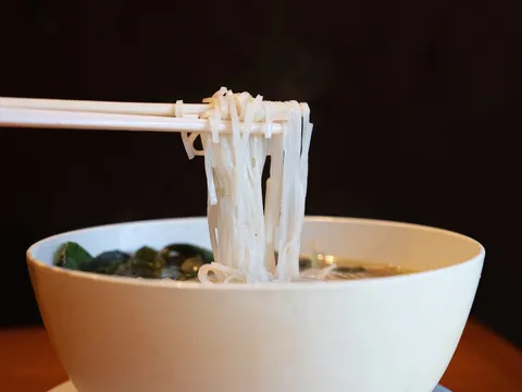 Chopsticks lifting rice noodles from a steaming bowl of pho at Mai Lee in Brentwood, Missouri