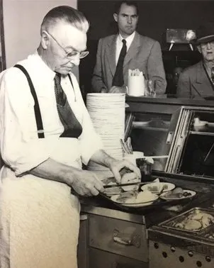 Historic black-and-white photo of Philippe Mathieu preparing sandwiches at Philippe the Original